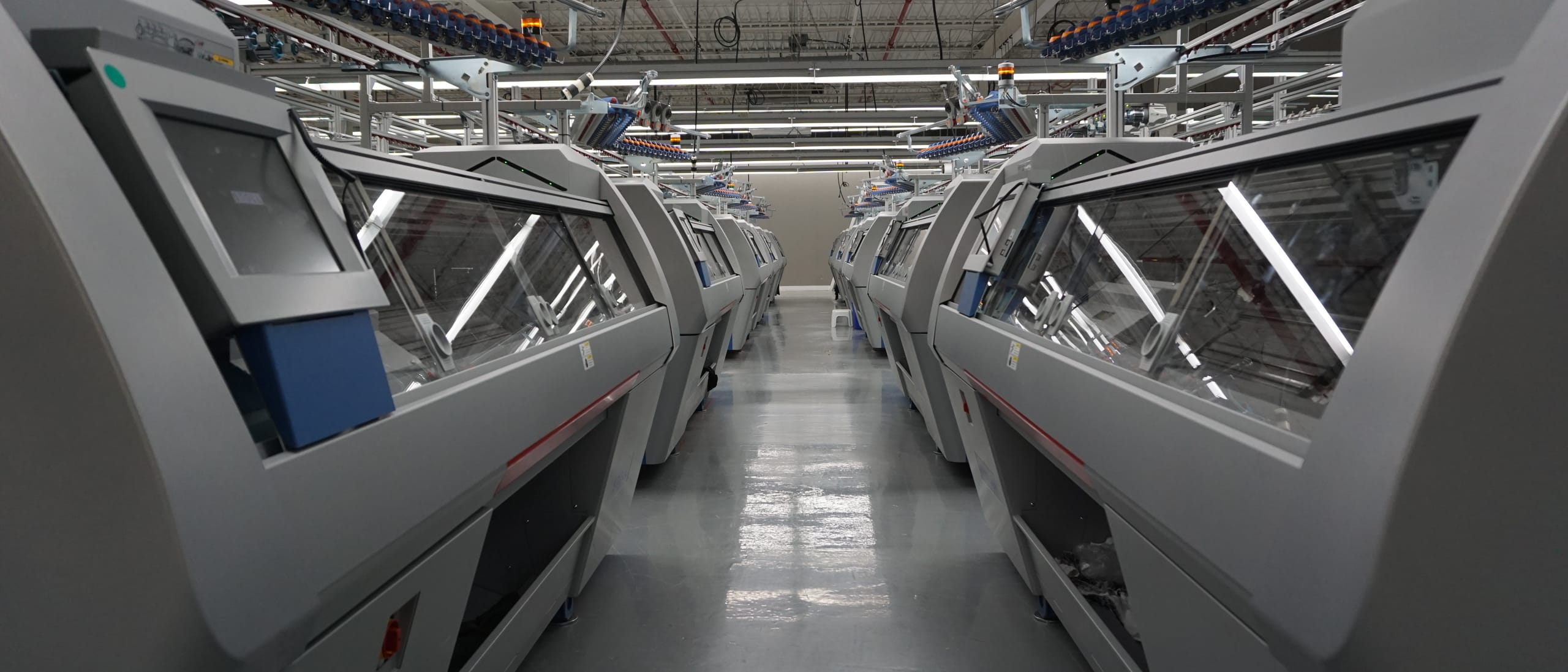 The consolidated Mississauga floor — flat-knitting machines running the length of the hall