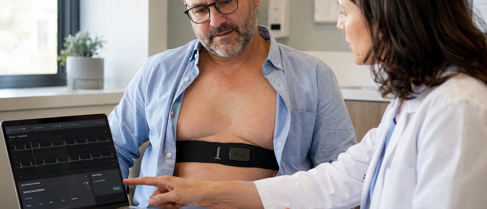 A clinician reviewing a 12-lead ECG with a patient wearing a SKIIN cardiac band