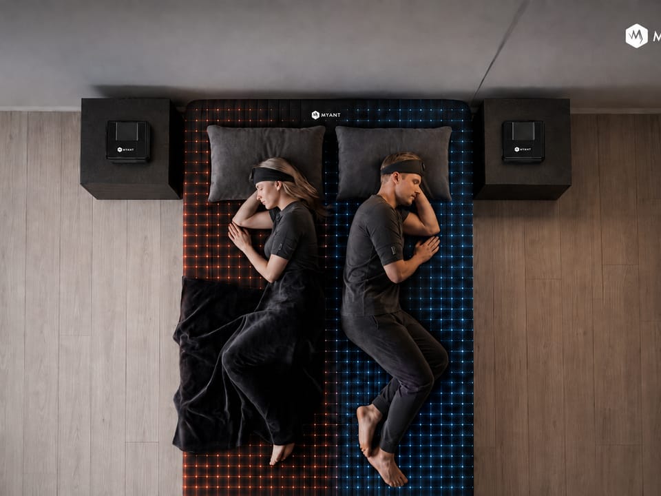 Overhead view of two sleepers on a dual-zone sensing bed, one side lit warm and the other cool