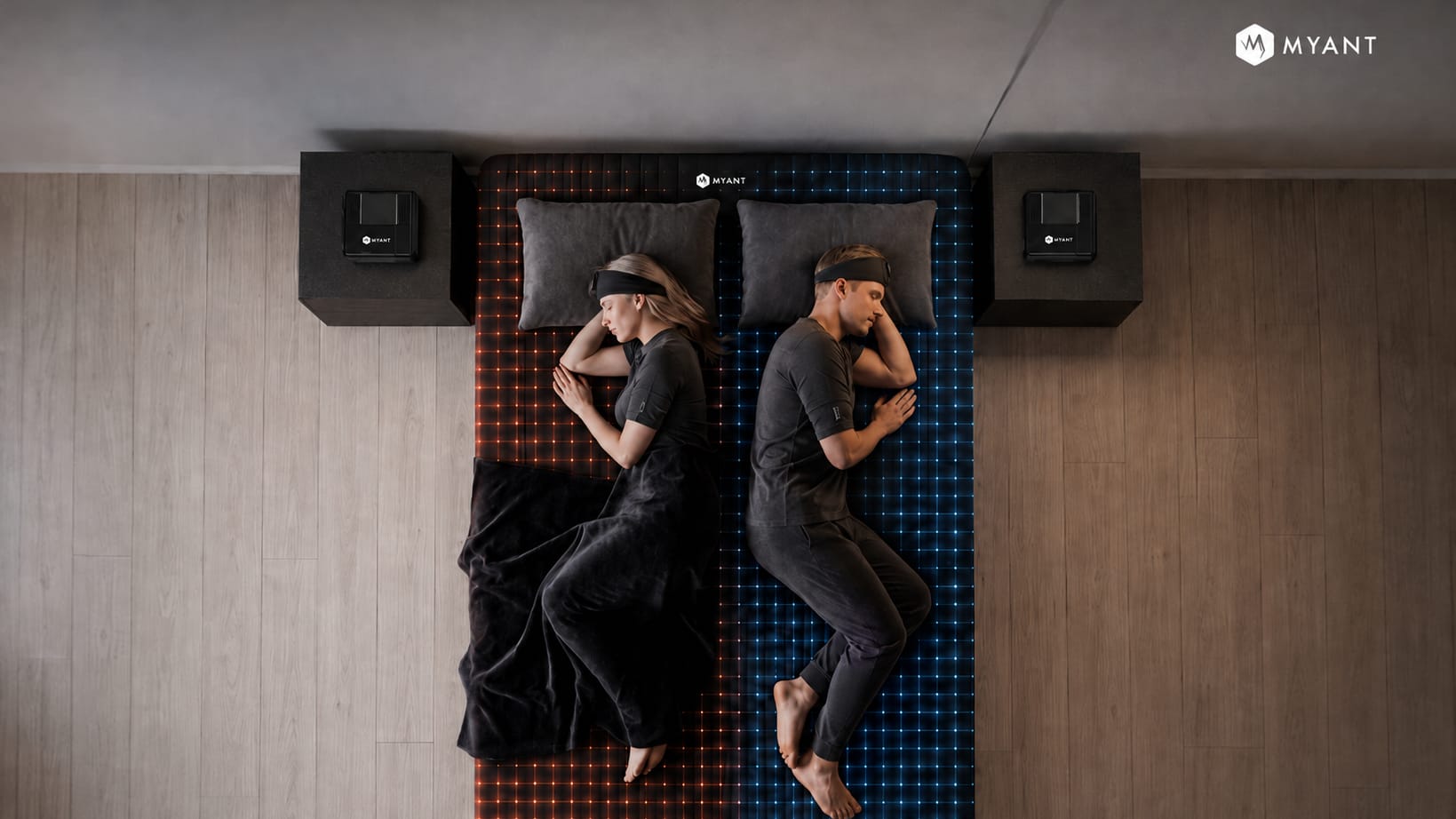 Overhead view of two sleepers on a dual-zone sensing bed — the left zone lit warm, the right zone lit cool