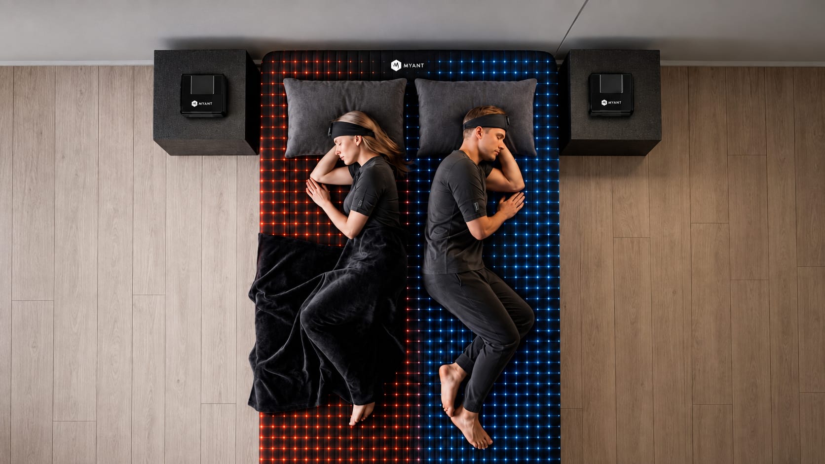 Overhead view of two sleepers on a dual-zone sensing bed — the left zone lit warm, the right zone lit cool