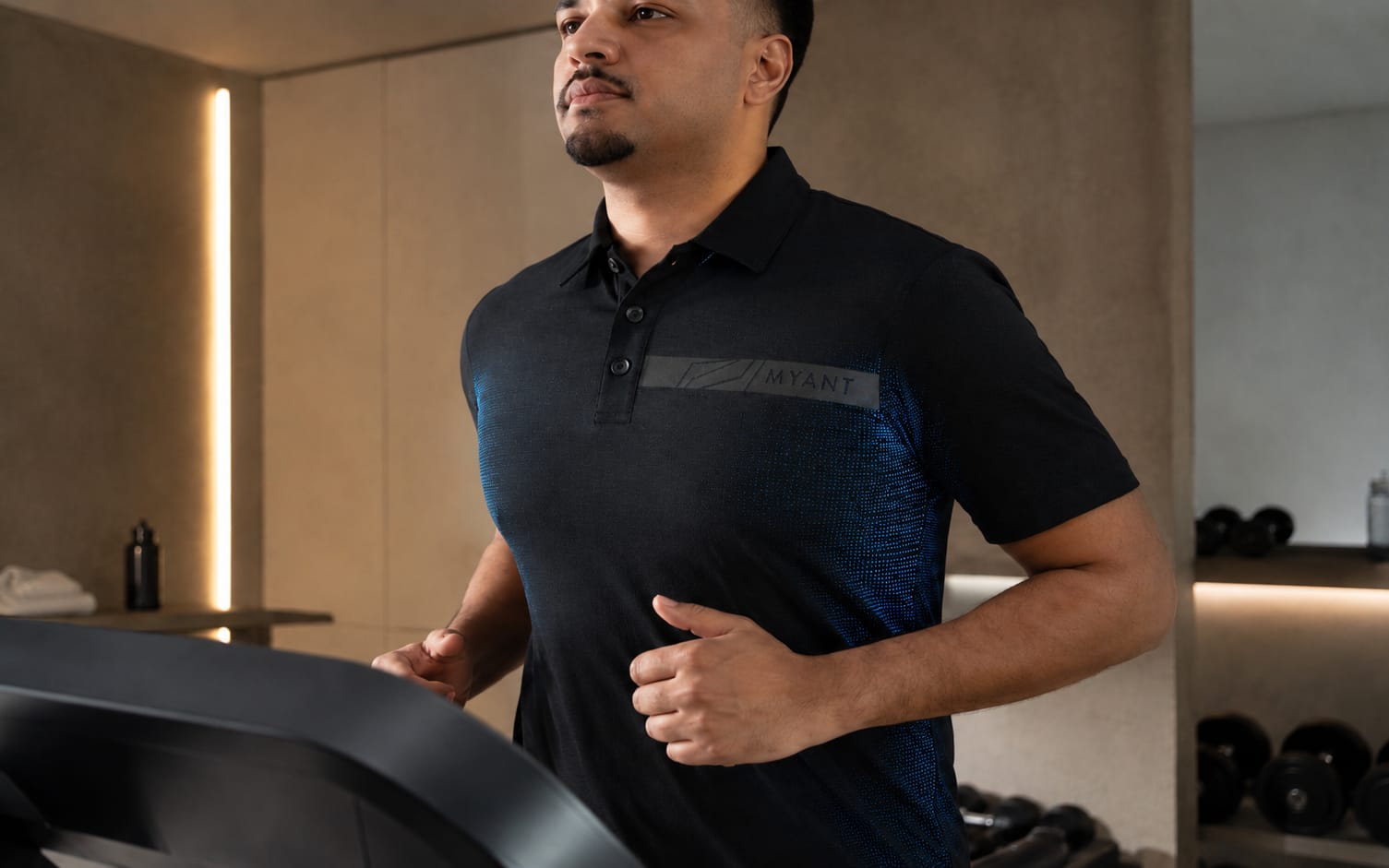 A connected MYANT knitted polo worn on a treadmill — sensing textile in an everyday training setting