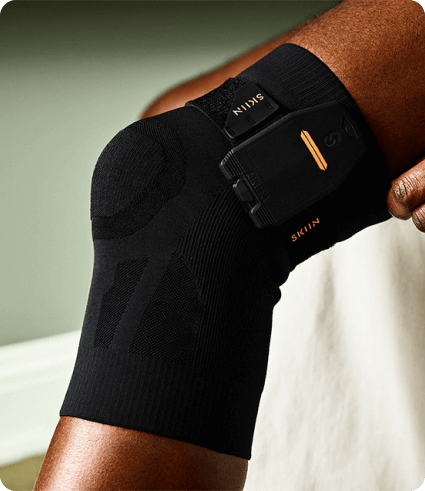 A patient wearing a knee strap equipped with Skiin technology.